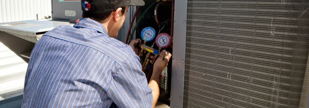 HVAC technician servicing a condenser unit in Lyndon